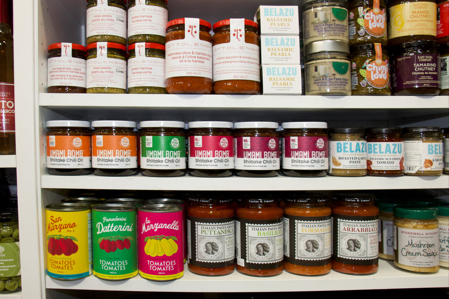 Shelf with various jars of condiments and sauces with visible labels.